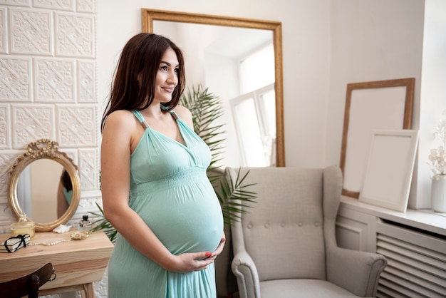 Pregnant woman holding her belly and looking away