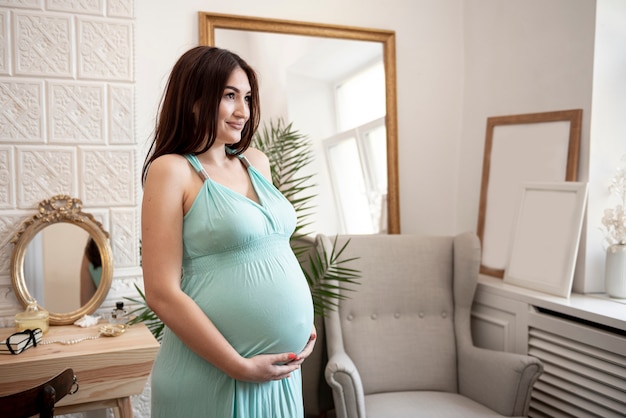 Беременная женщина, держа ее живот и глядя