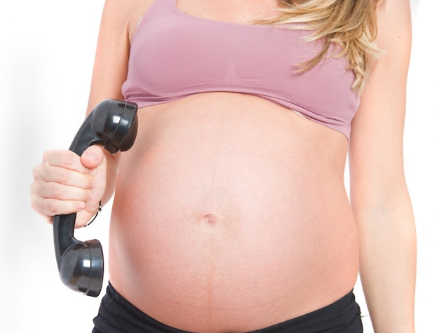 Pregnant woman holding old phone to belly