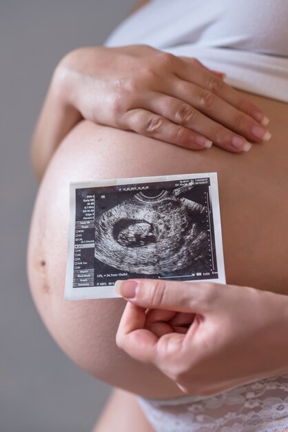 Pregnant woman holding photo of her future baby