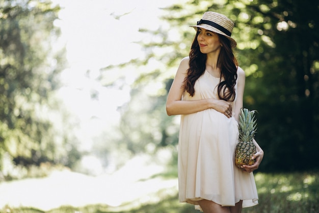 Free photo pregnant woman holding pineapple