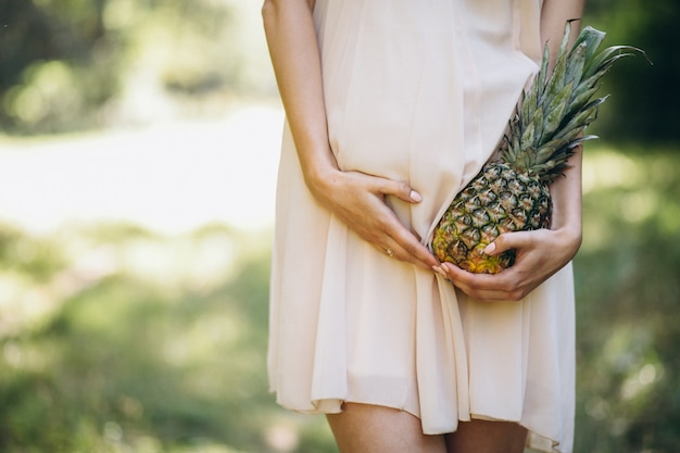 パイナップルを持っている妊娠中の女性