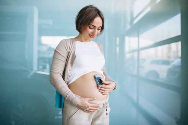 腹で小さな車のモデルを保持している妊娠中の女性