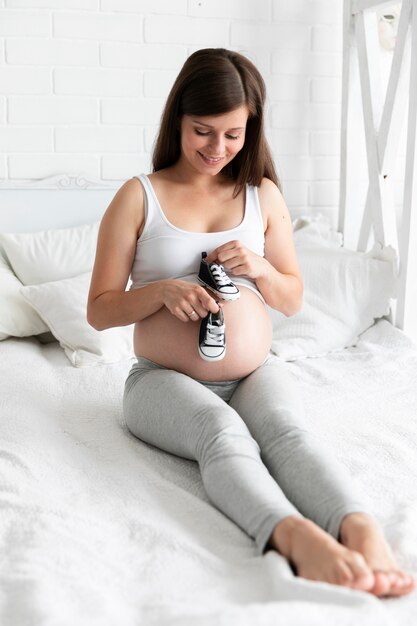 彼女の赤ちゃんのための小さな靴を保持している妊娠中の女性