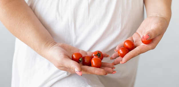 Pregnant woman holding some cherry tomatoes close-up