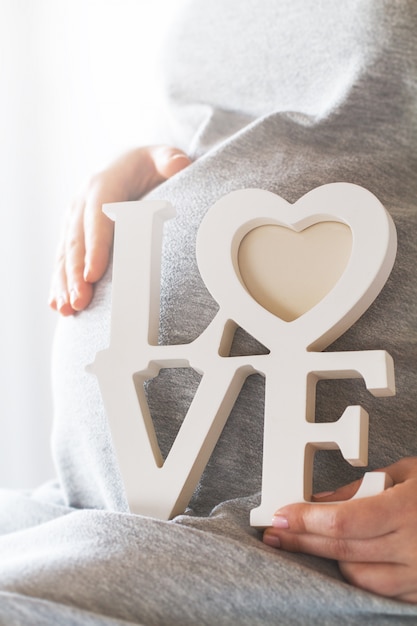 Pregnant woman holding the word "love"