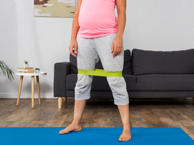 Pregnant woman at home exercising with elastic band