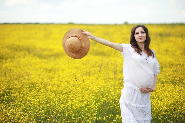 Беременная женщина в платье в поле цветов