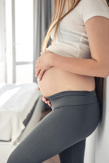 Foto gratuita donna incinta all'interno della stanza su uno sfondo sfocato