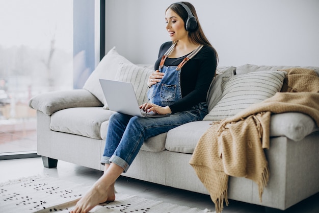 Pregnant woman listening to music in earphones and surfing the internet