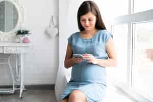 Free photo pregnant woman looking on her phone