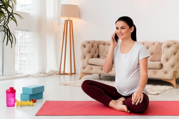 Pregnant woman in lotus position talking on the phone with copy space