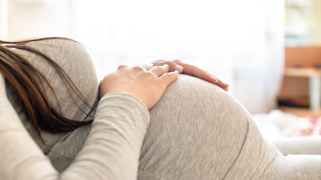 Pregnant woman lying on the bed and holding her belly