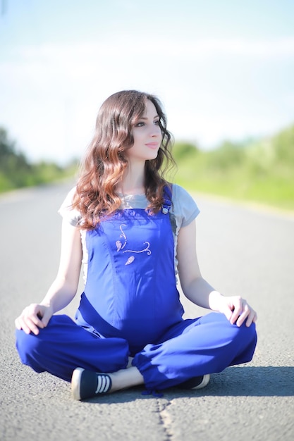 Беременная женщина на дорожной йоге Premium Фотографии