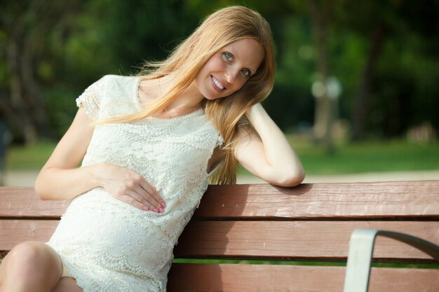 夏の公園のベンチで妊娠中の女性