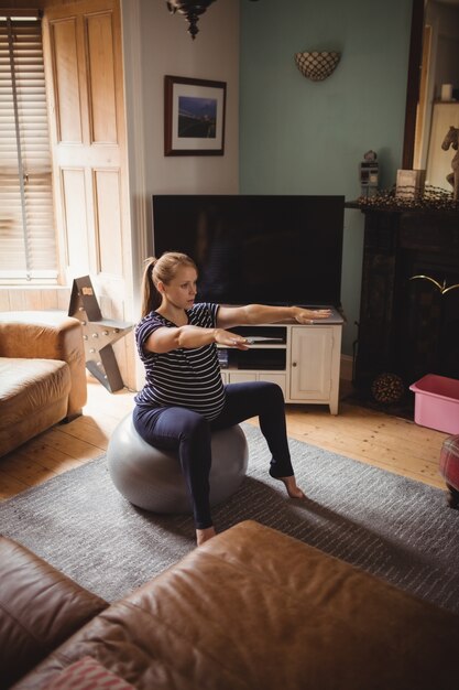 임신 한 여자는 거실에서 피트니스 공에 스트레칭 운동을 수행