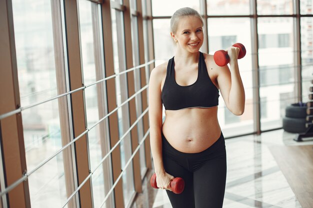 Беременная женщина занимается спортом с гантелями