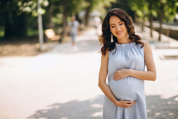 Беременная женщина позирует в парке
