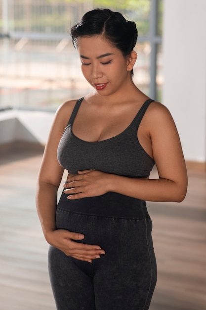 Foto gratuita donna incinta che pratica yoga al chiuso