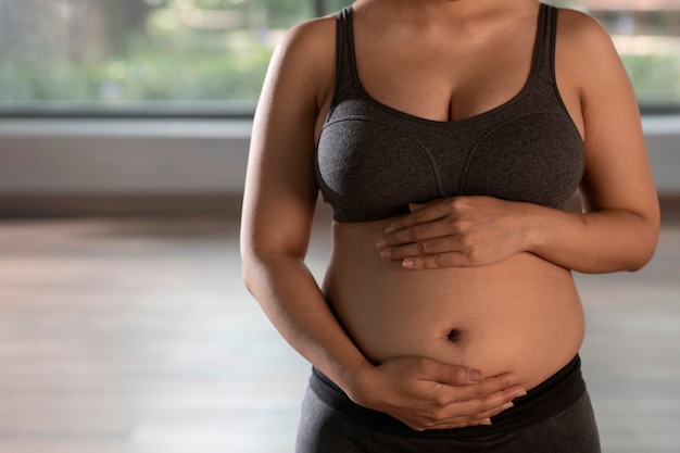 Donna incinta che pratica yoga al chiuso