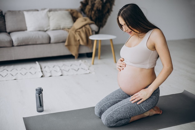 Foto gratuita donna incinta che pratica yoga sul tappetino a casa