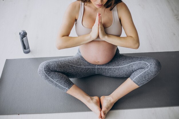 Pregnant woman practicing yoga on mat at home