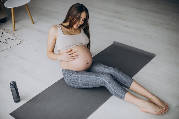 Pregnant woman practicing yoga on mat at home