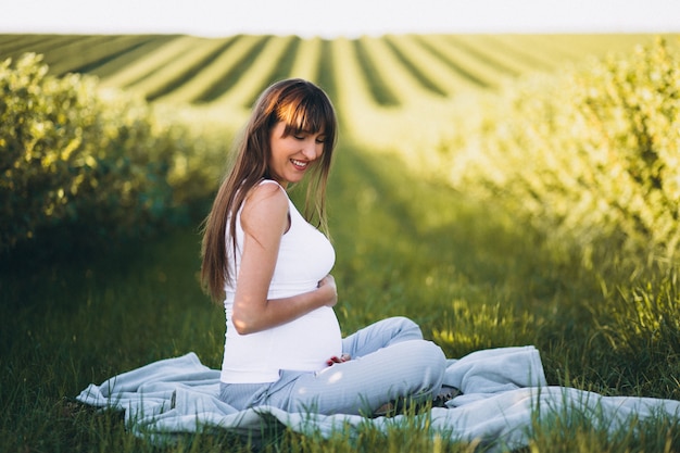 Free photo pregnant woman practising yoga in field