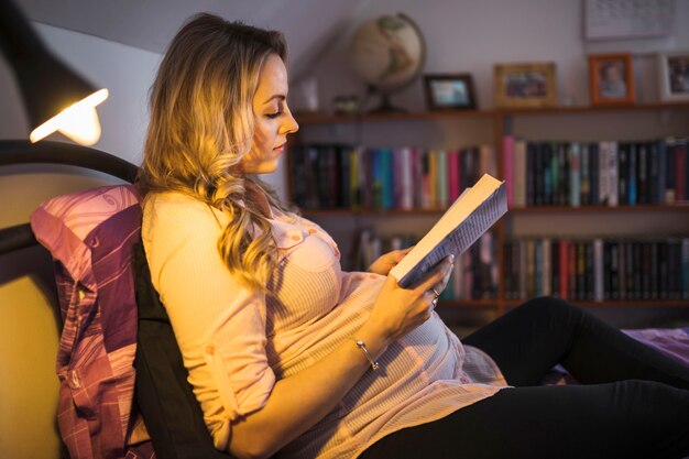 Pregnant woman reading book at night