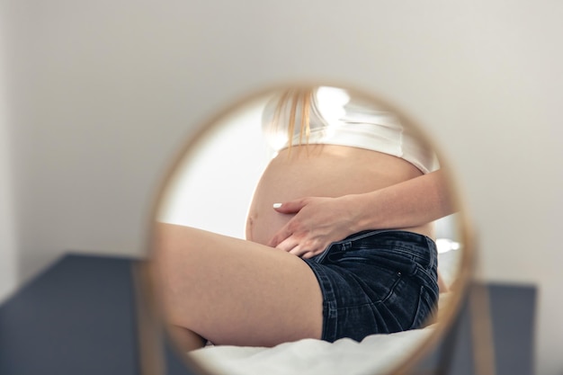 Foto gratuita riflessione della donna incinta della pancia nel primo piano dello specchio