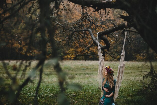 Pregnant woman rests outside on the rope swing hanging 