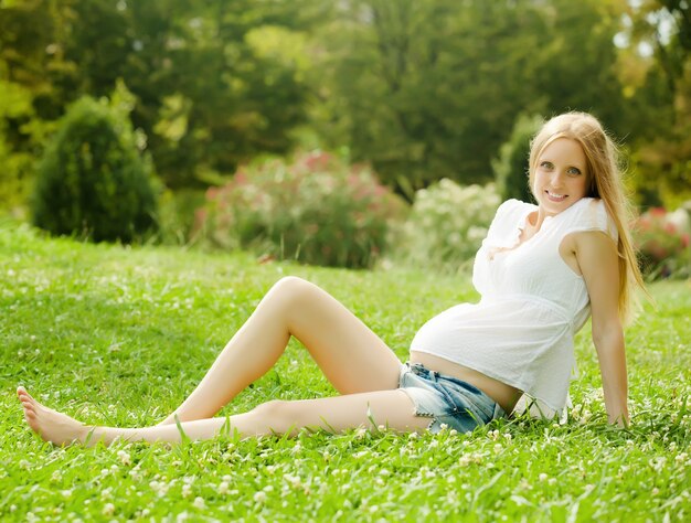 草の上に座っている妊婦