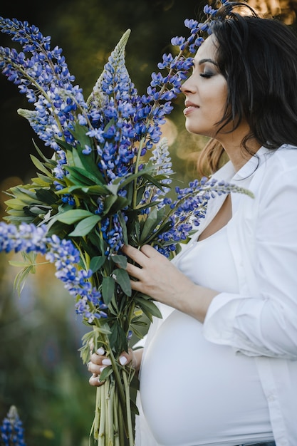 Pregnant woman smells a bouquet of lupines