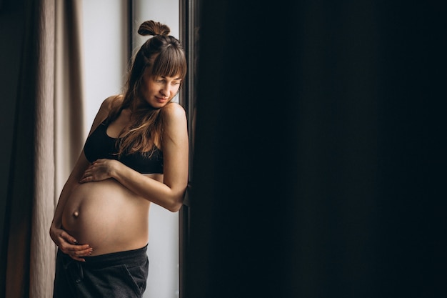 Foto gratuita donna incinta in piedi vicino alla finestra