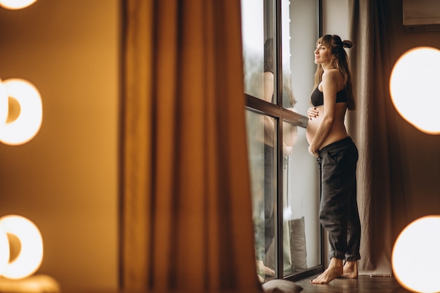 Беременная женщина, стоя у окна