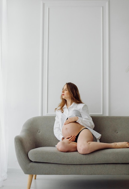 Pregnant woman in the studio In a white shirt