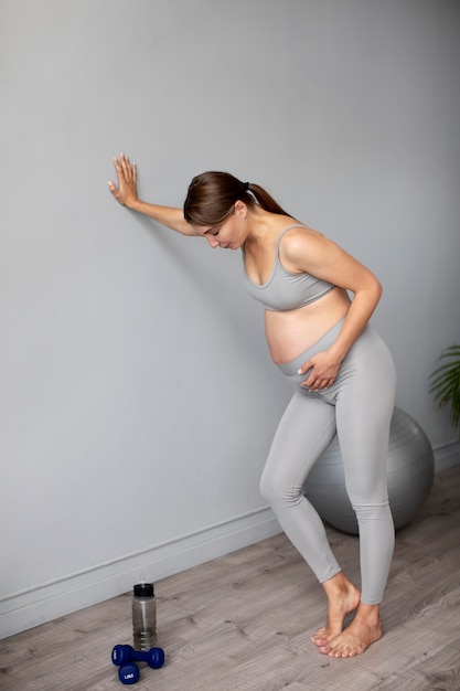 Pregnant woman taking a break from exercising at home