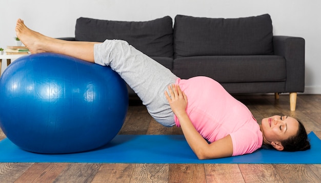 Pregnant woman training at home on the floor with ball