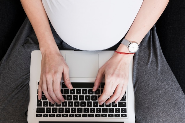 Pregnant woman typing on keyboard