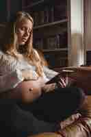 無料写真 リビングルームでデジタルタブレットを使用して妊娠中の女性