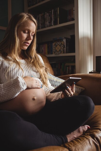 リビングルームでデジタルタブレットを使用して妊娠中の女性