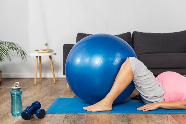 Беременная женщина, используя мяч для упражнений дома