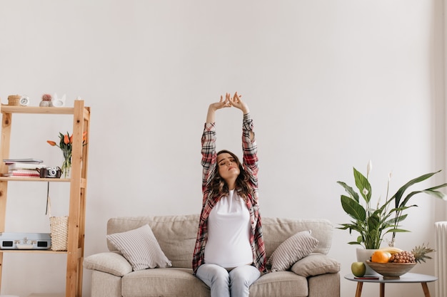 Pregnant woman in white tee and plaid shirt stretches