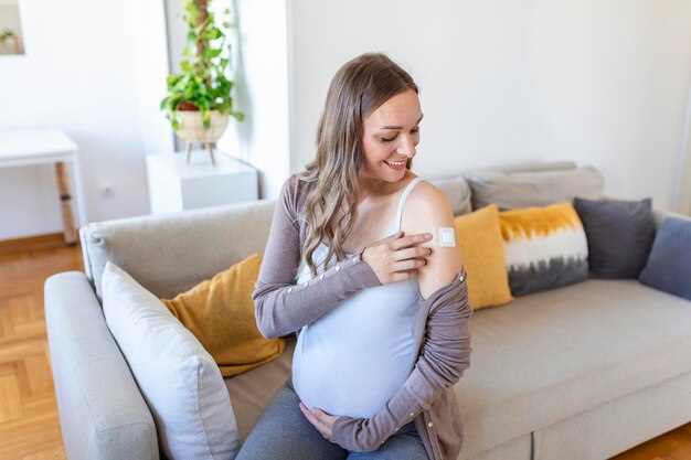 コロナウイルスワクチンの後に彼女の腕に絆創膏を持っている妊婦応急処置医療薬局とヘルスケアの概念