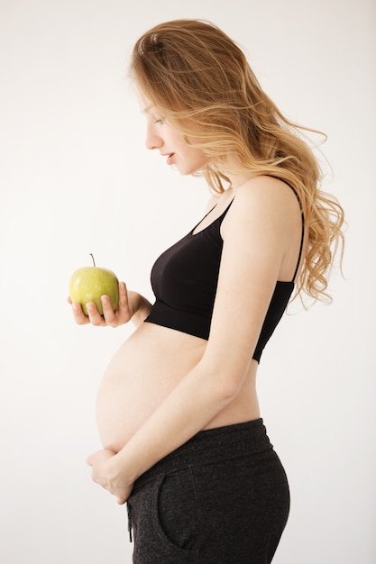 pregnant woman with blond hair in home clothes with open stomach