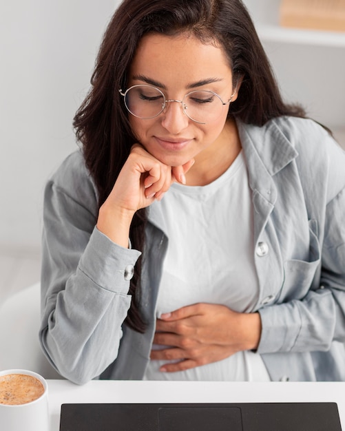 Pregnant woman with glasses working on laptop from home