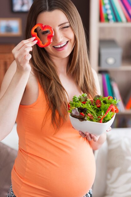 Pregnant woman with healthy salad at home