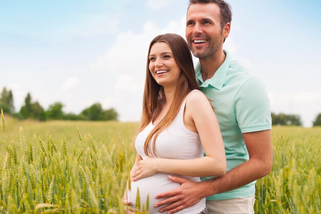 Pregnant woman with her man in the summer field