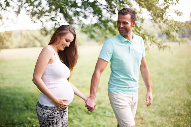 牧草地を歩いている夫と妊娠中の女性