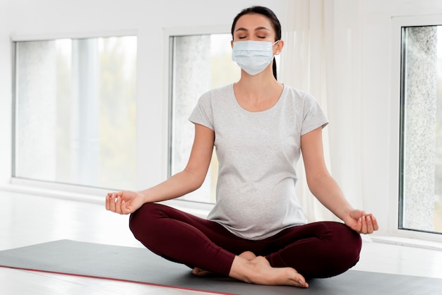 Pregnant woman with medical mask meditating